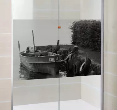 Shower Decal - A black and white still shot of a young boy sitting along side a docked wooden boat. A distinctive feature great for the bathroom